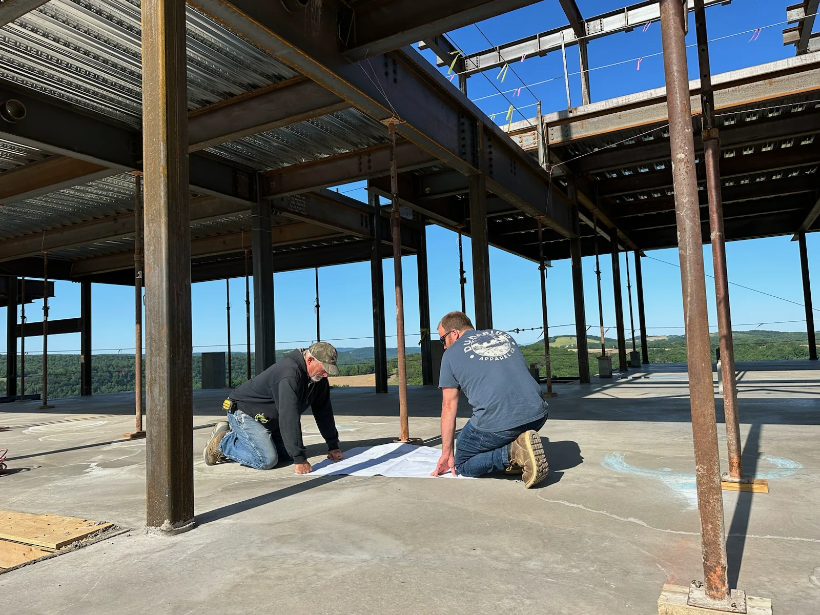 Will Hidlay and a contractor reviewing drawings inside a steel-framed house under construction