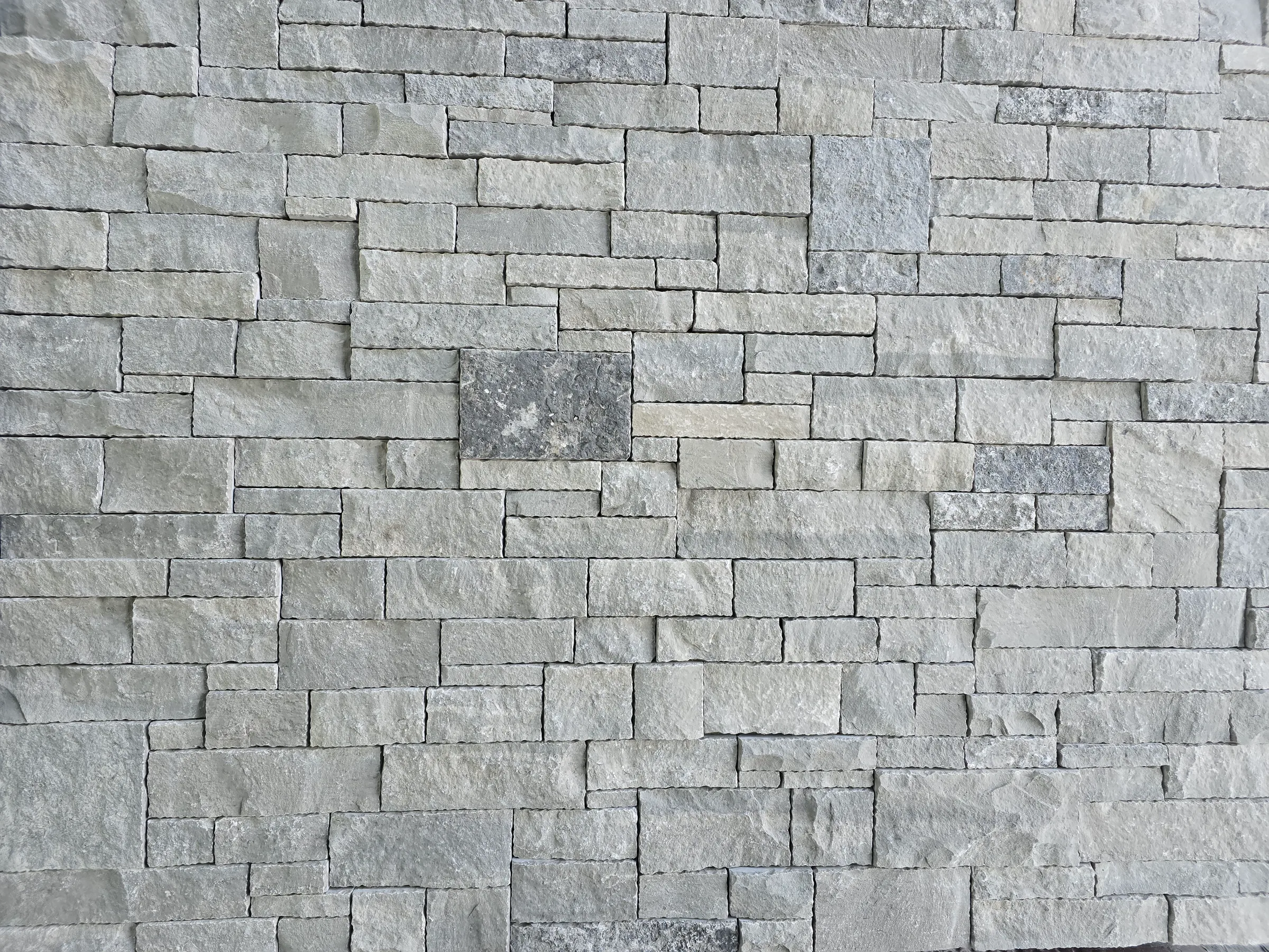 Dry-stack ledgestone wall in cool gray tones, with a darker accent block left of center