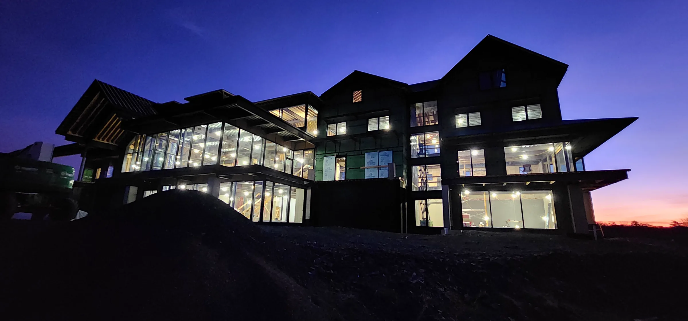 Glazed structural shell of the Modern Mountain House illuminated at blue hour