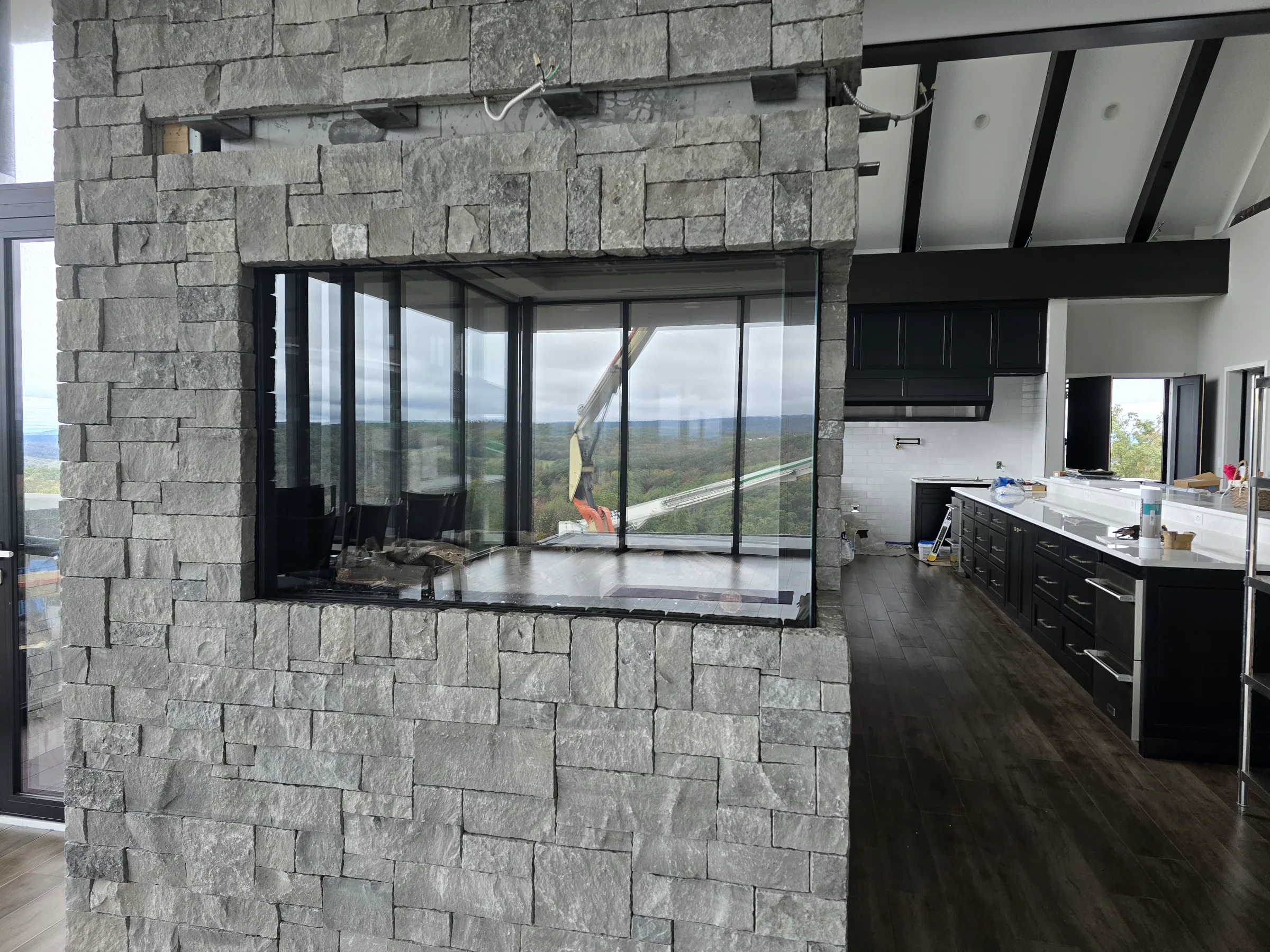 Stone partition and dark kitchen cabinetry inside the Modern Mountain House