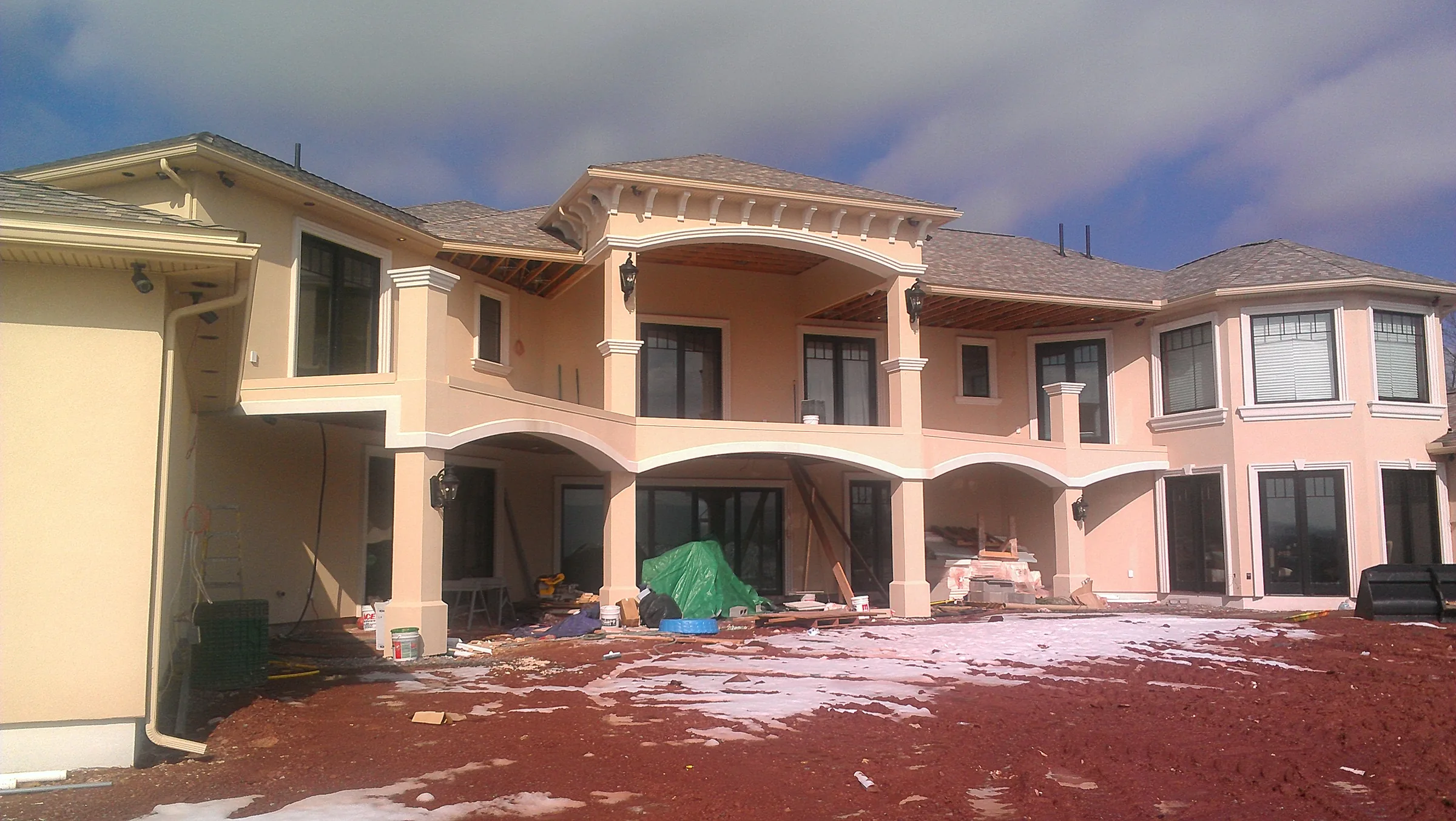 Rear elevation of the residence during late-stage construction, showing the arched loggia before finish work is complete