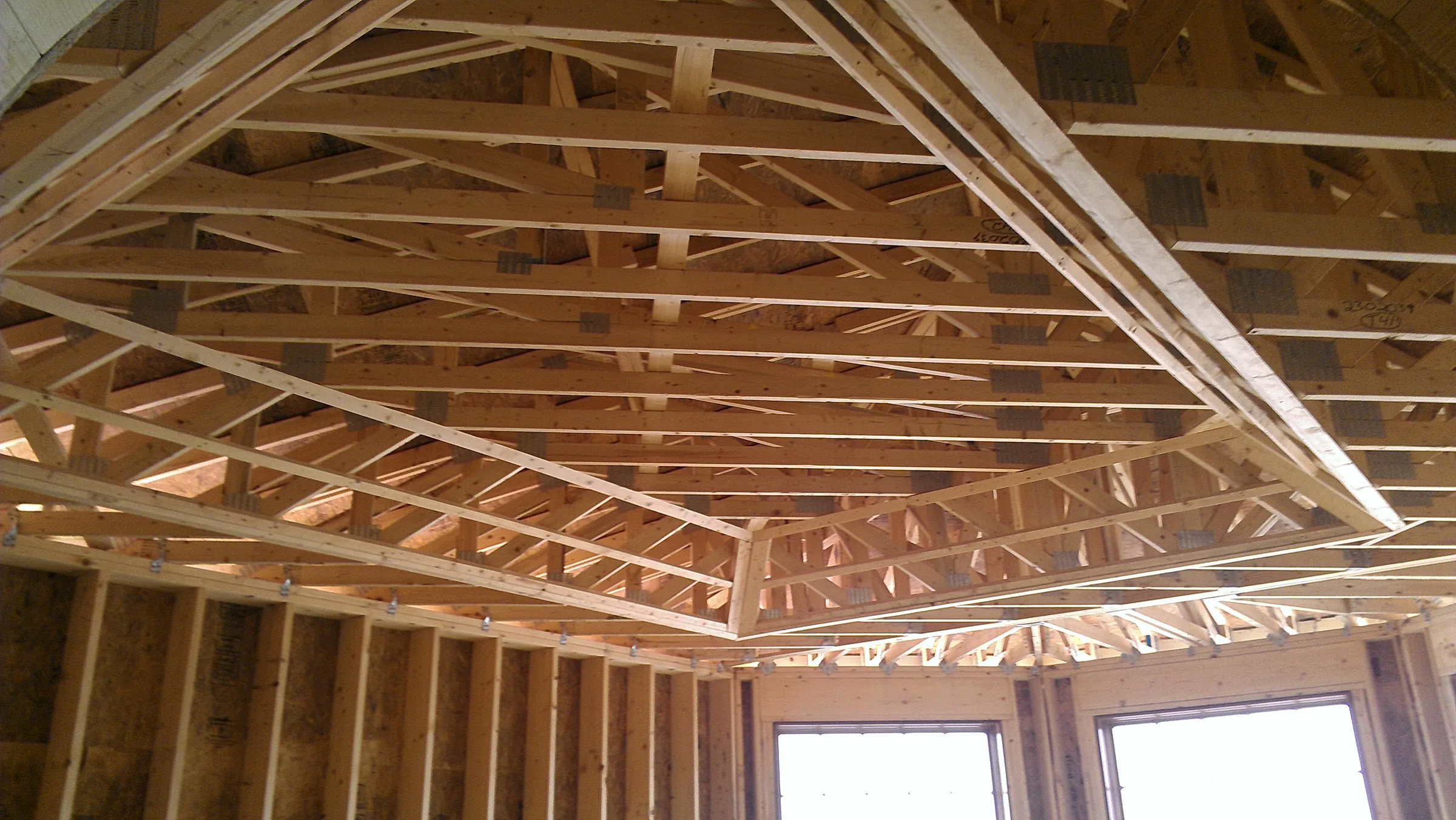 Detail view of hip-roof truss framing and blocking from below during construction