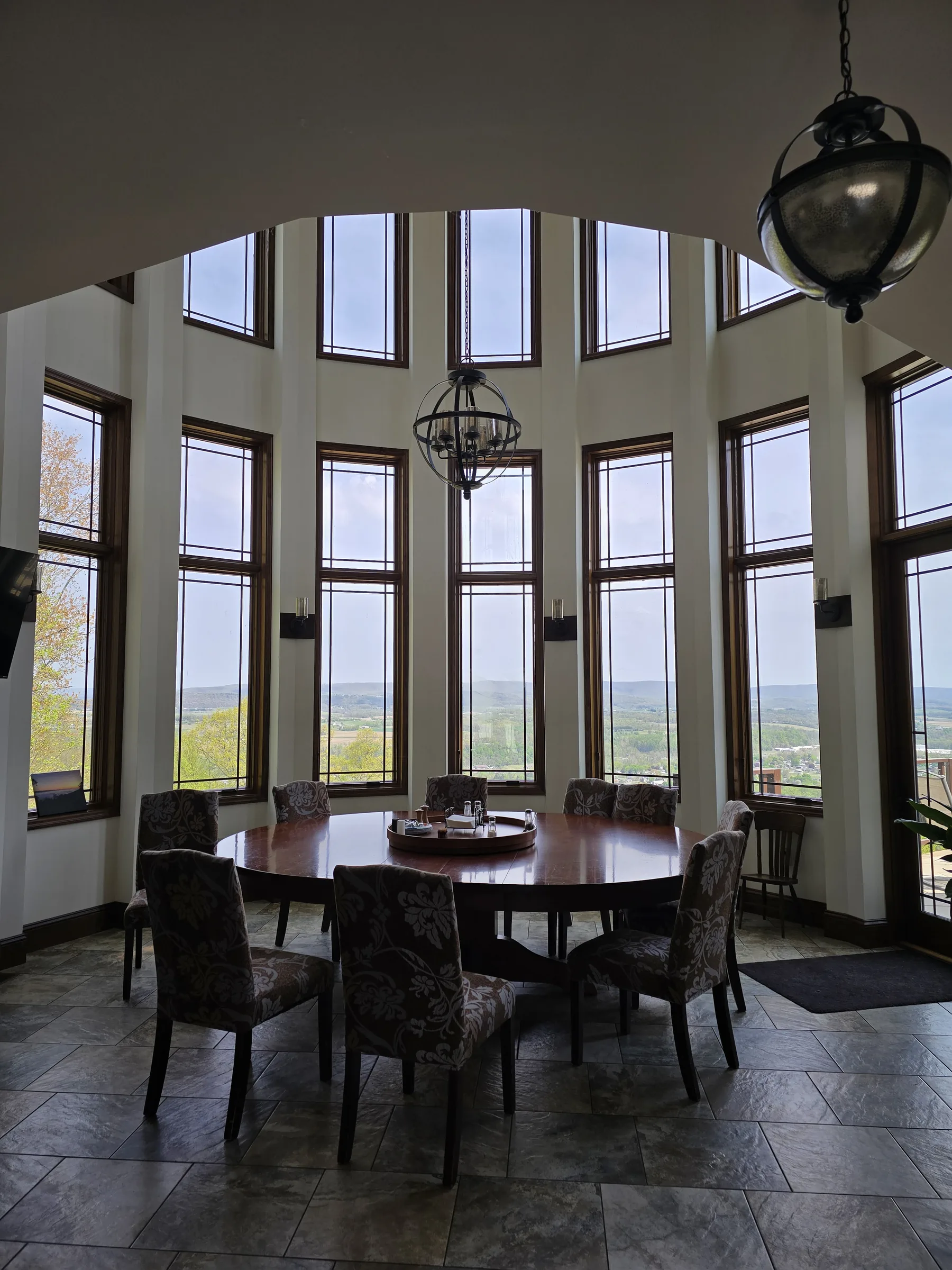 Round breakfast table beneath clerestory windows overlooking a river valley