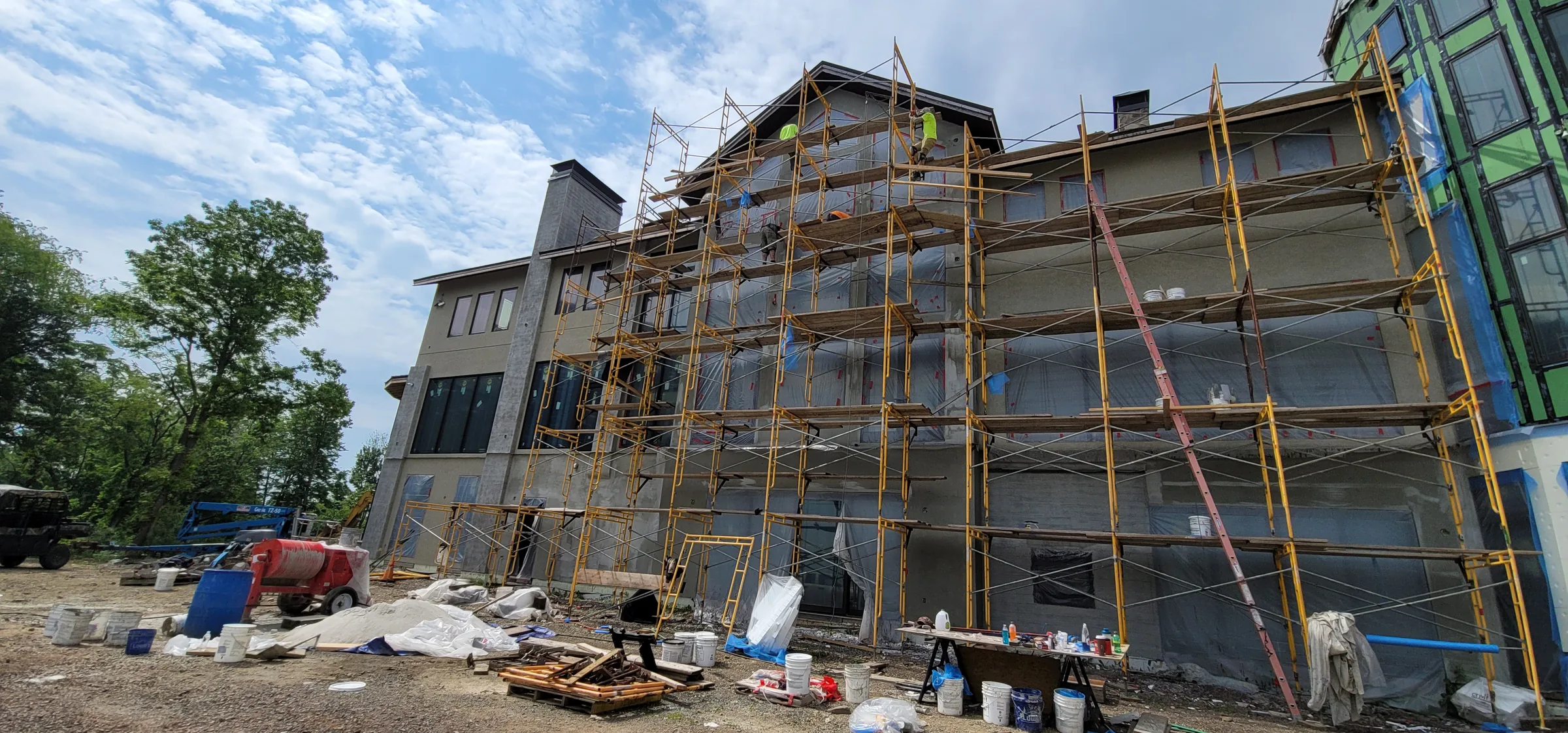 Multi-story residence under scaffolding during stucco and stone veneer installation