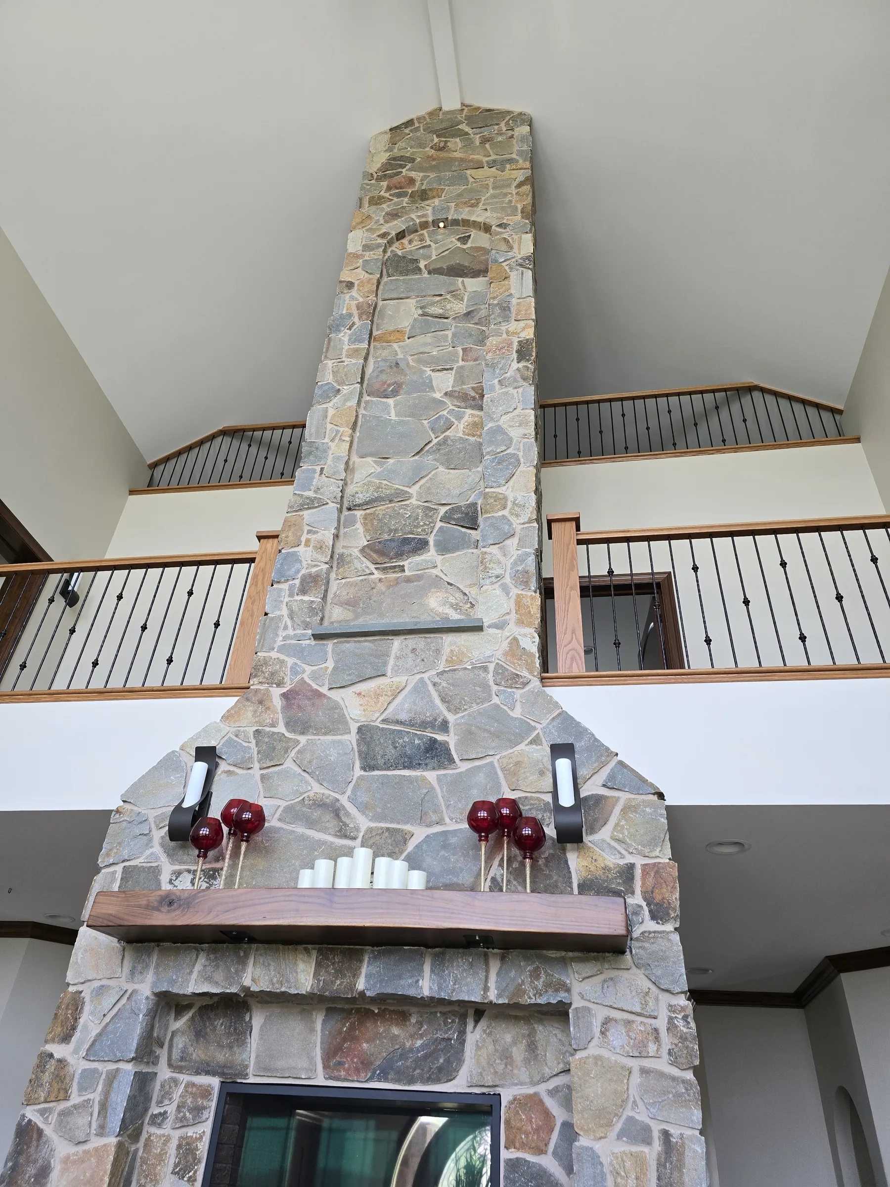 Rough-cut fieldstone chimney breast with wrought-iron sconces