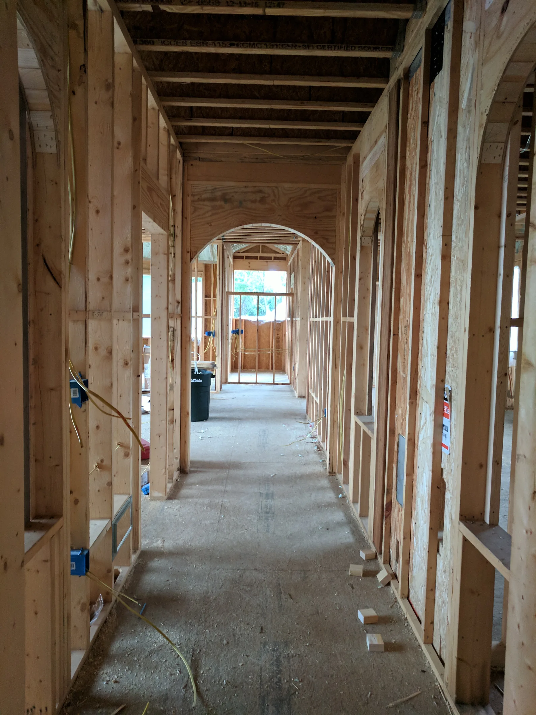 Unfinished timber-framed corridor with a sequence of arched openings