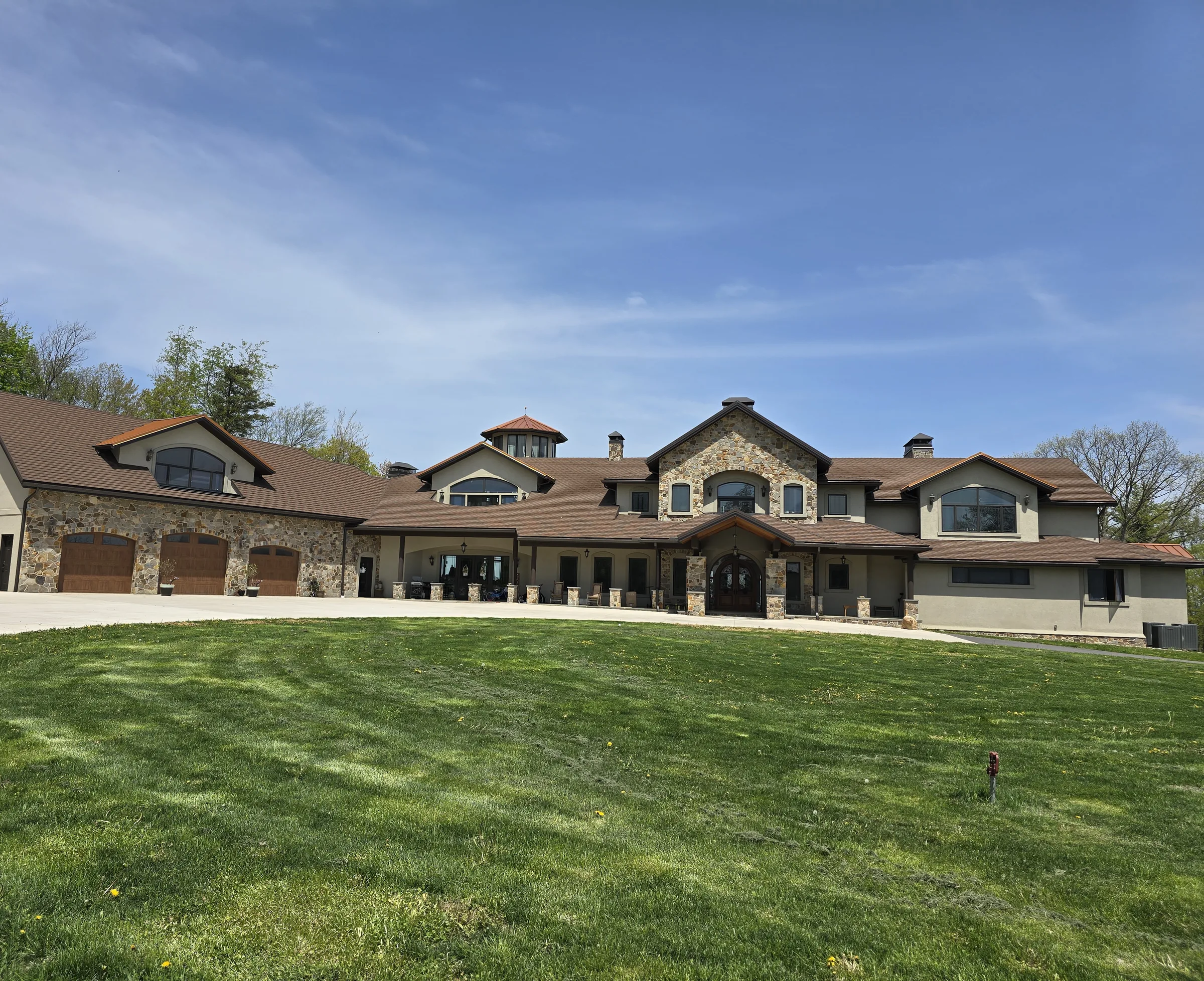 Completed stone and stucco front elevation with an arched entry and three-car garage
