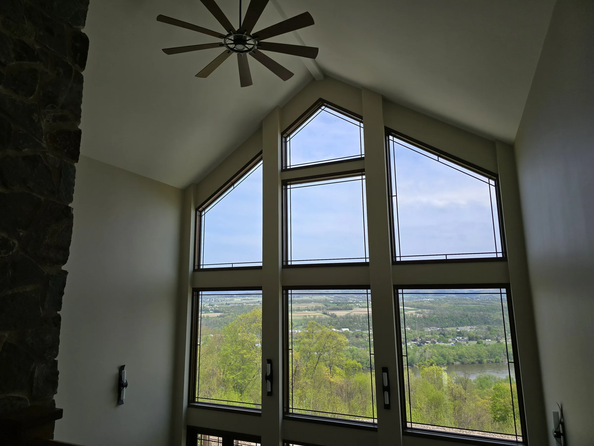 Vaulted great room with a floor-to-ceiling window wall overlooking a forested river valley