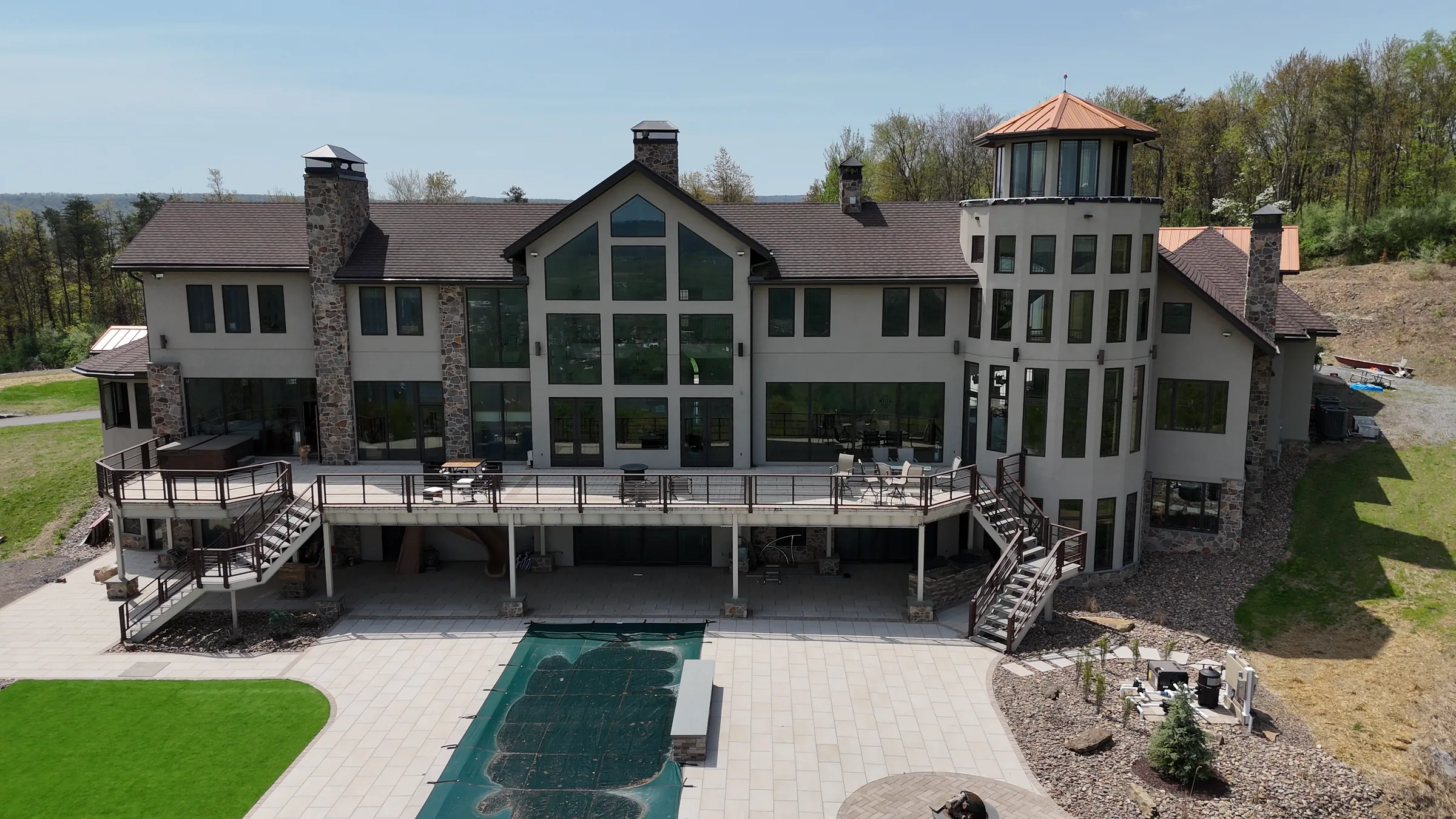 Aerial view of the completed rear elevation with a wraparound deck, twin exterior stairs, and glazed tower