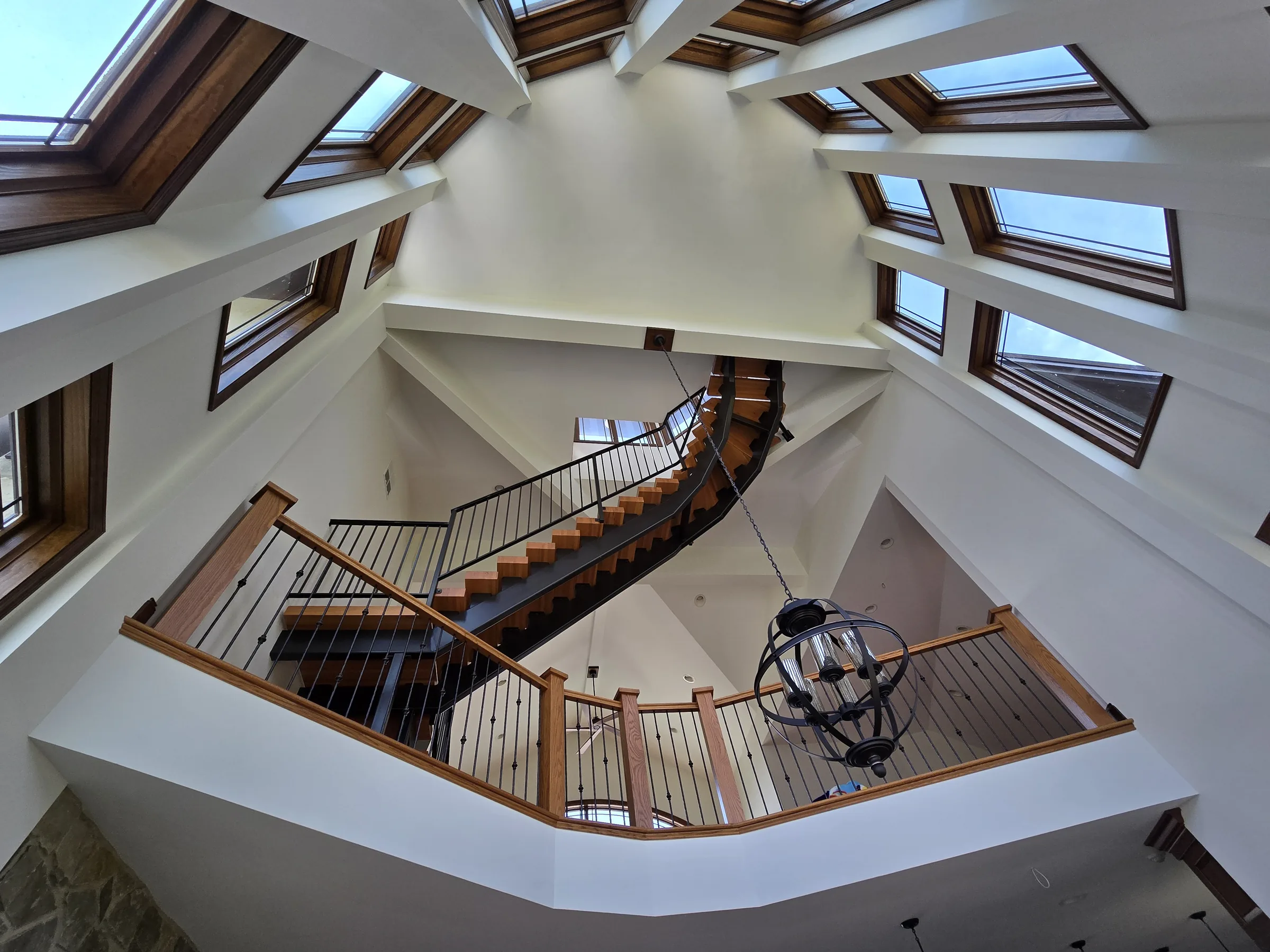 Octagonal skylight tower above a curved wood-and-steel staircase