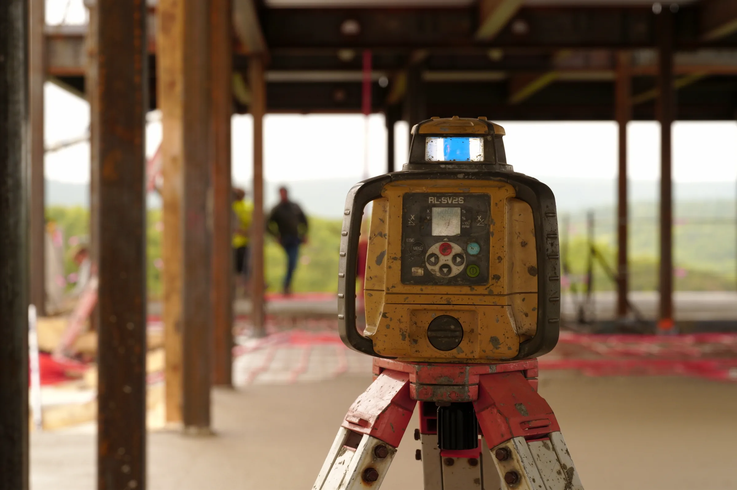 Rotary laser level set within a steel-framed building to verify field layout and elevations
