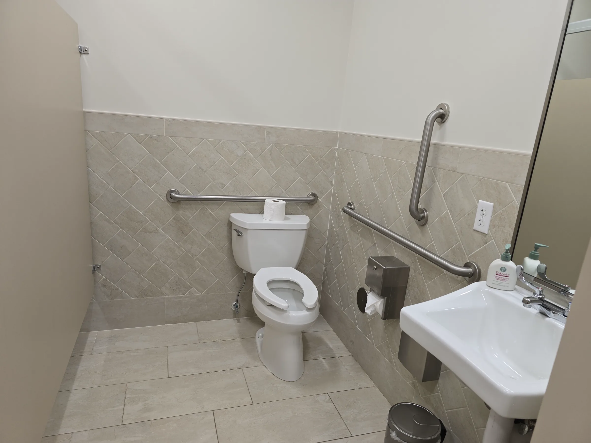 Completed accessible bathroom at Calvary Church showing the sink, toilet, grab bars, and durable tile finishes